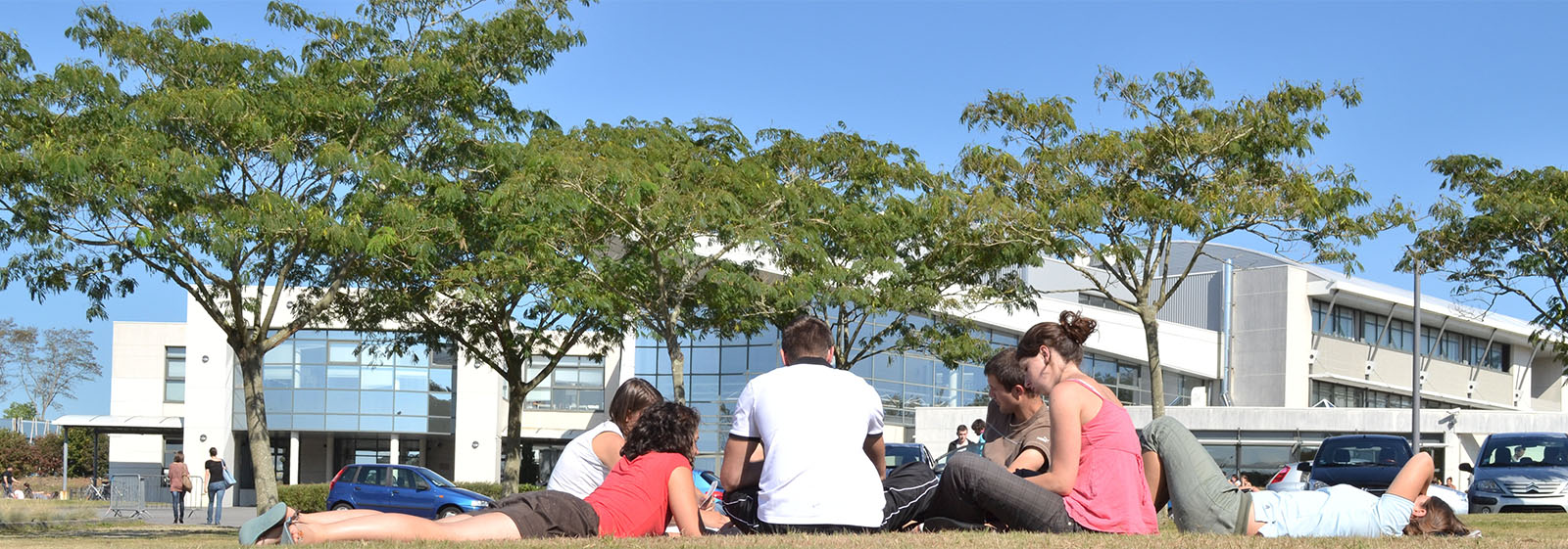 Groupe d'étudiants assis par terre devant un campus